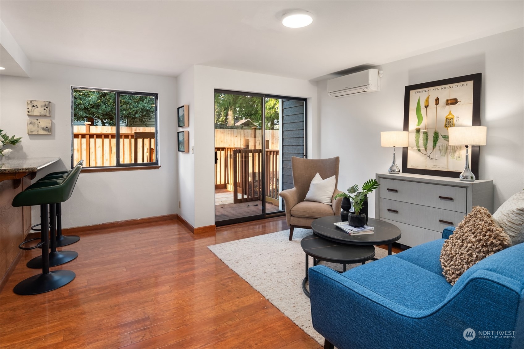 Living room with a blue sofa, wood floors, and sliding doors opening onto a deck.