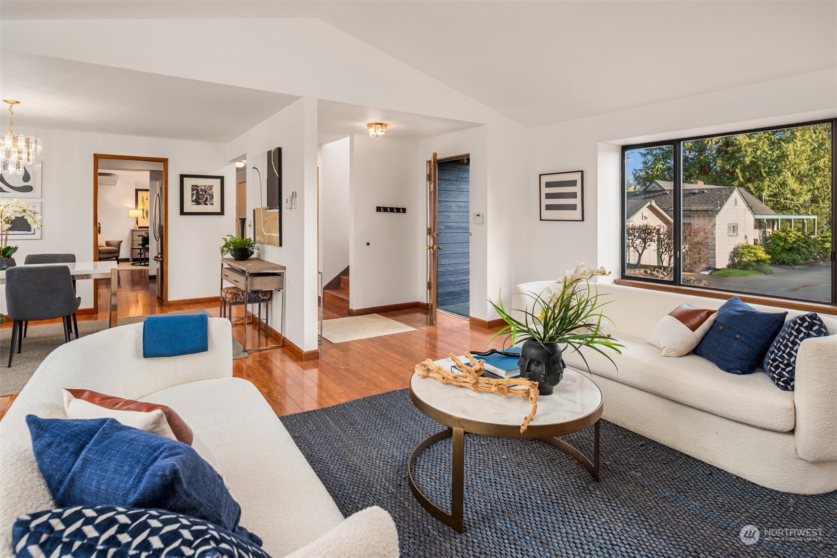 Staged living room with white sofas, a round coffee table, and a large picture window.