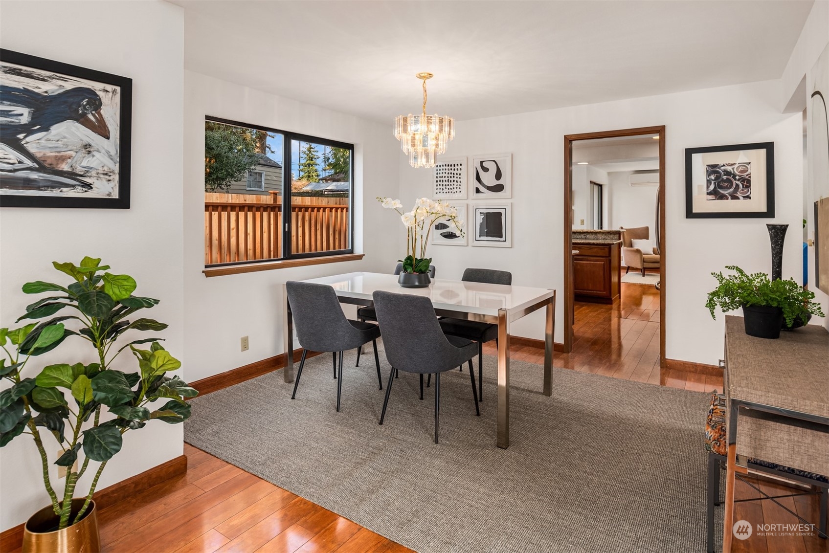 Dining room with a white table, gray chairs, chandelier, and hardwood floors.