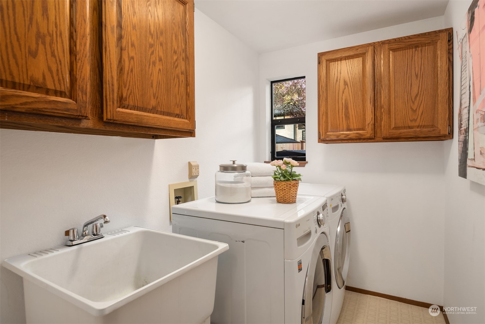 Laundry room with a utility sink, front-loading washer and dryer, and oak cabinets.