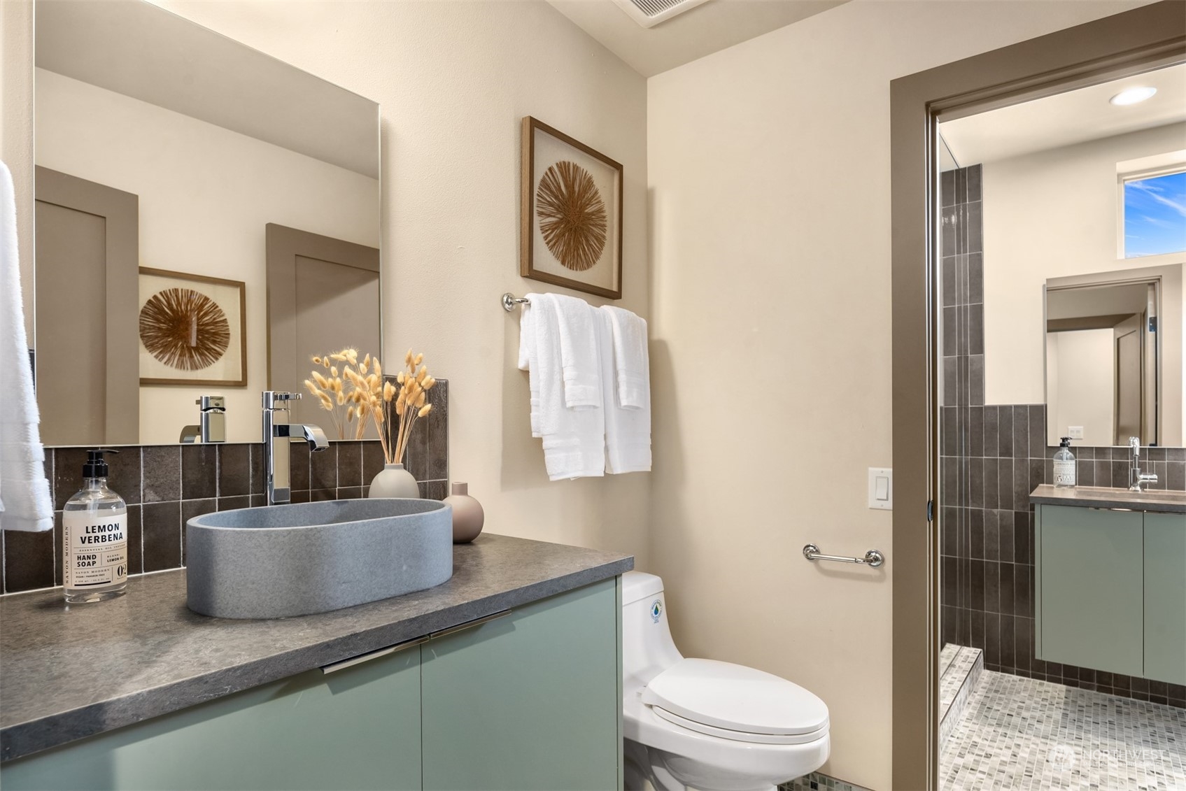 Bathroom with a gray vessel sink, pale green vanity, and tiled walk-in shower.