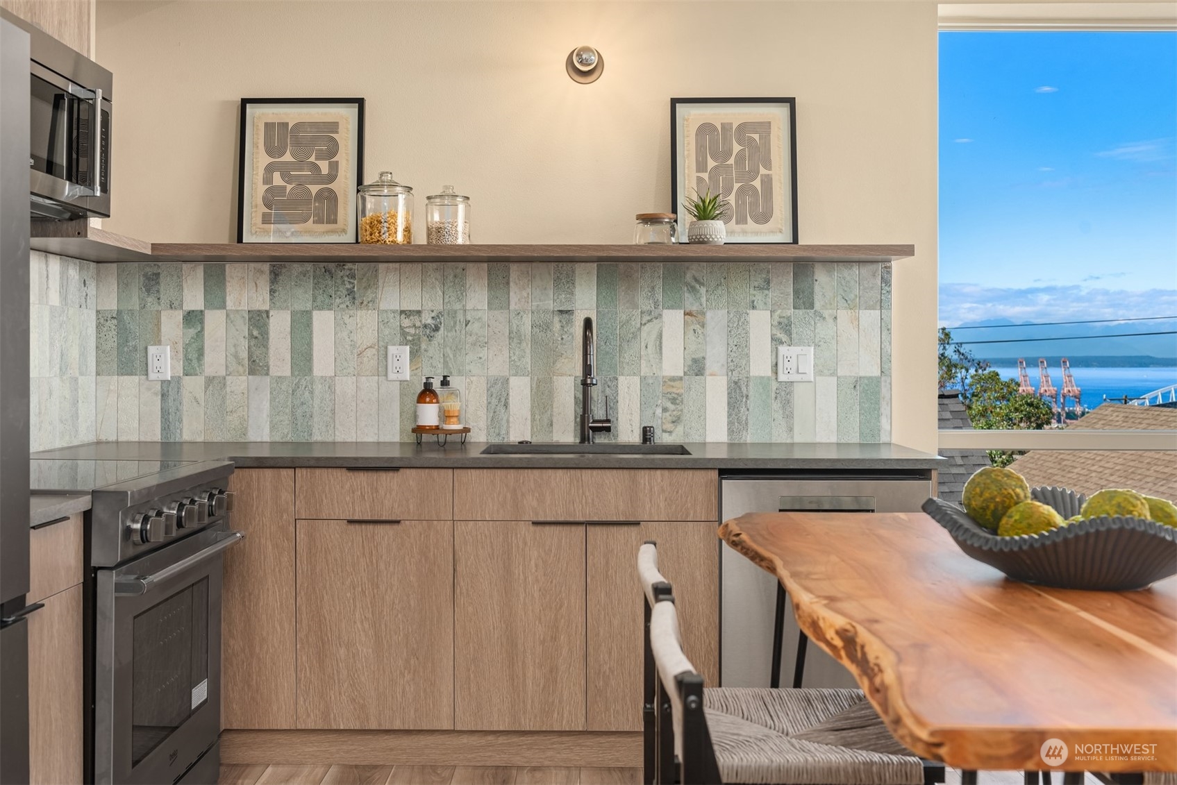 Modern kitchen with a green tile backsplash, live-edge dining table, and water view.