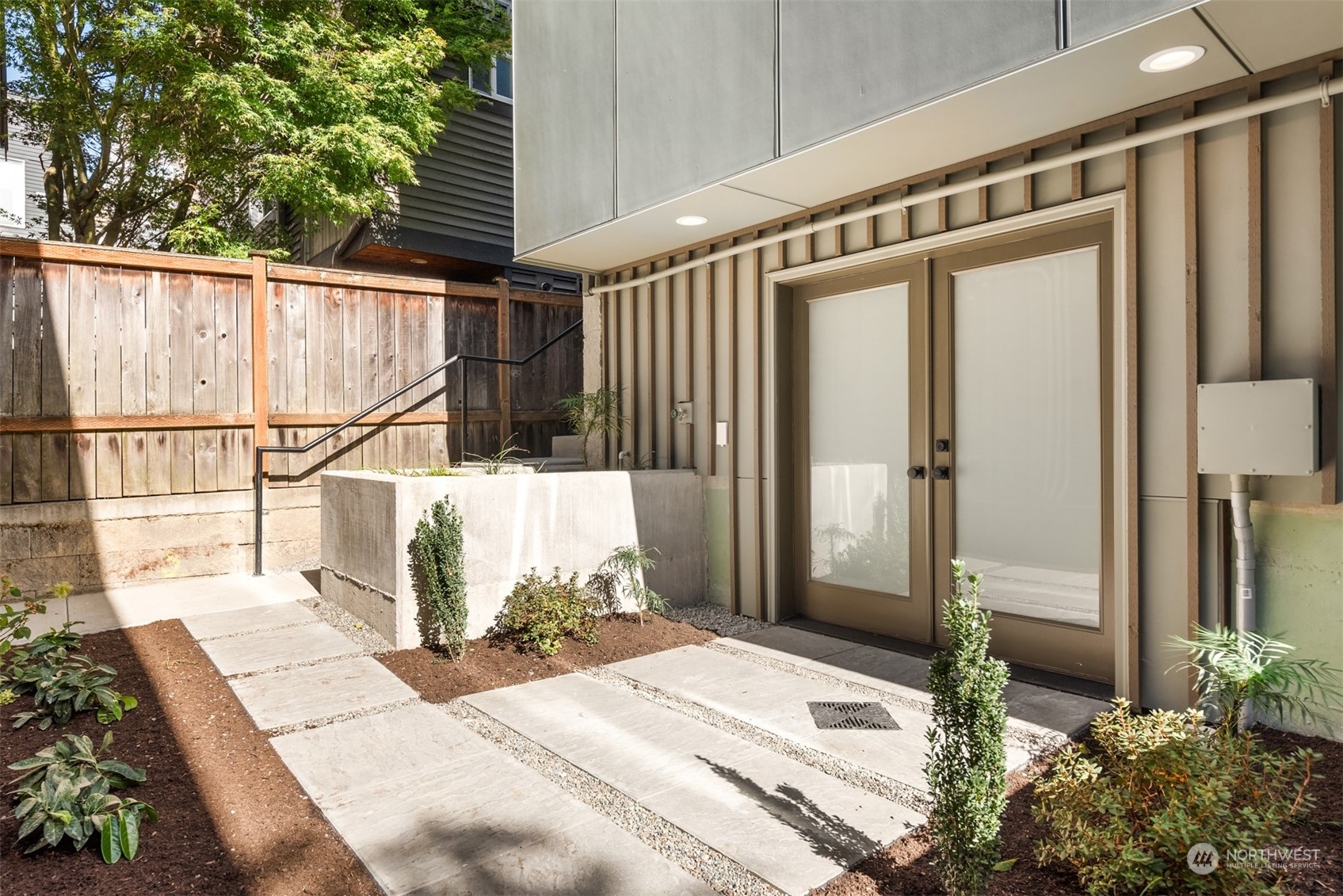 Modern home entrance with frosted-glass double doors and a landscaped concrete walkway.