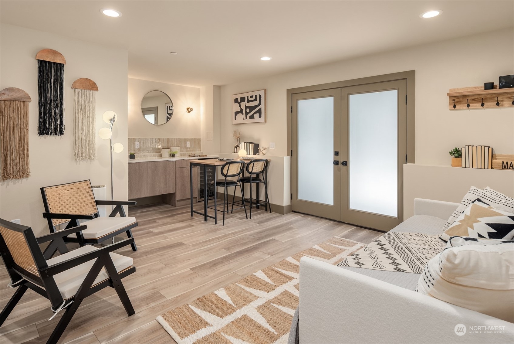 Furnished open-plan living area with a compact kitchenette, breakfast bar, and frosted-glass double doors.