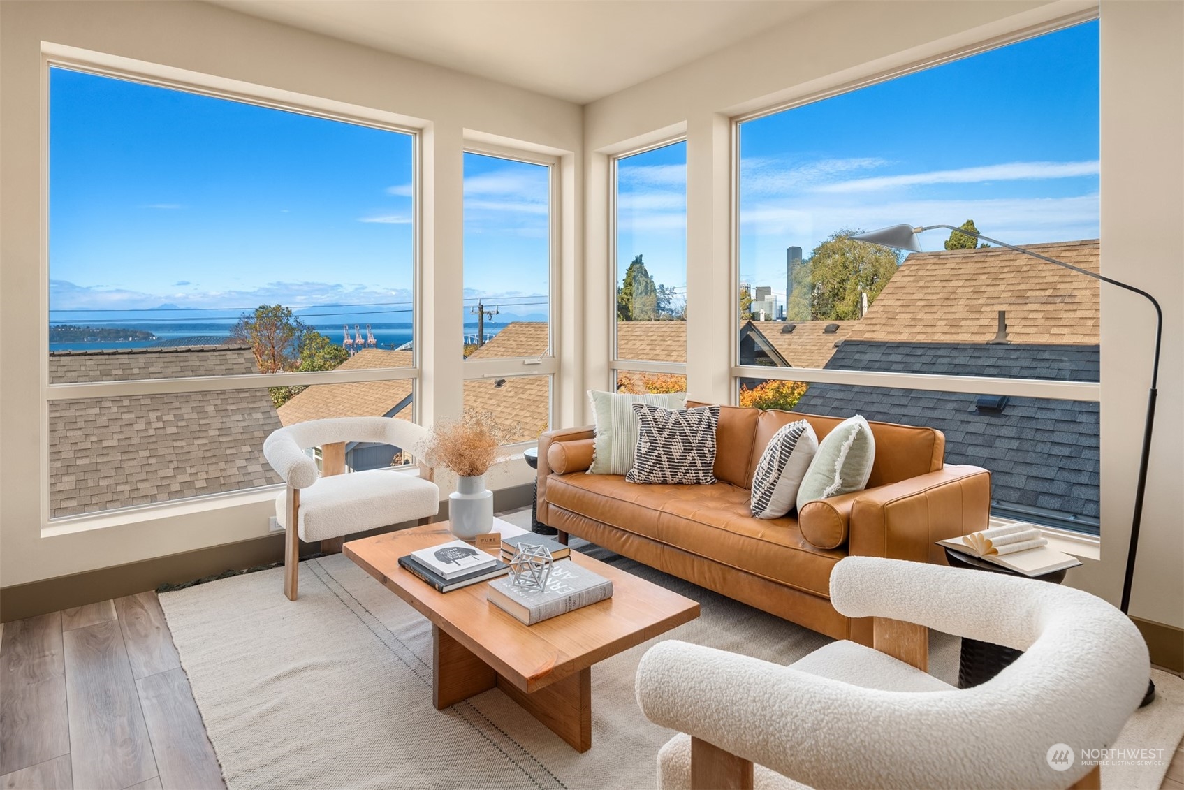 Staged living room with a caramel leather sofa and large windows overlooking the water.