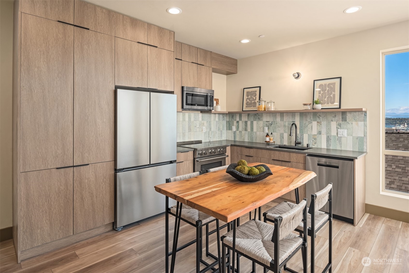 Modern kitchen with wood cabinetry, patterned tile backsplash, and a live-edge dining table.