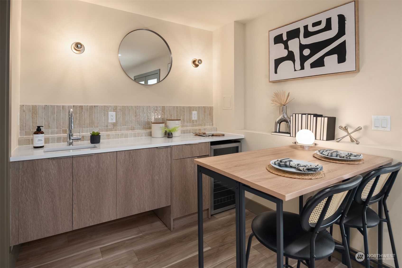 Kitchen and dining area with a tiled backsplash, long counter, and wood table with black chairs.