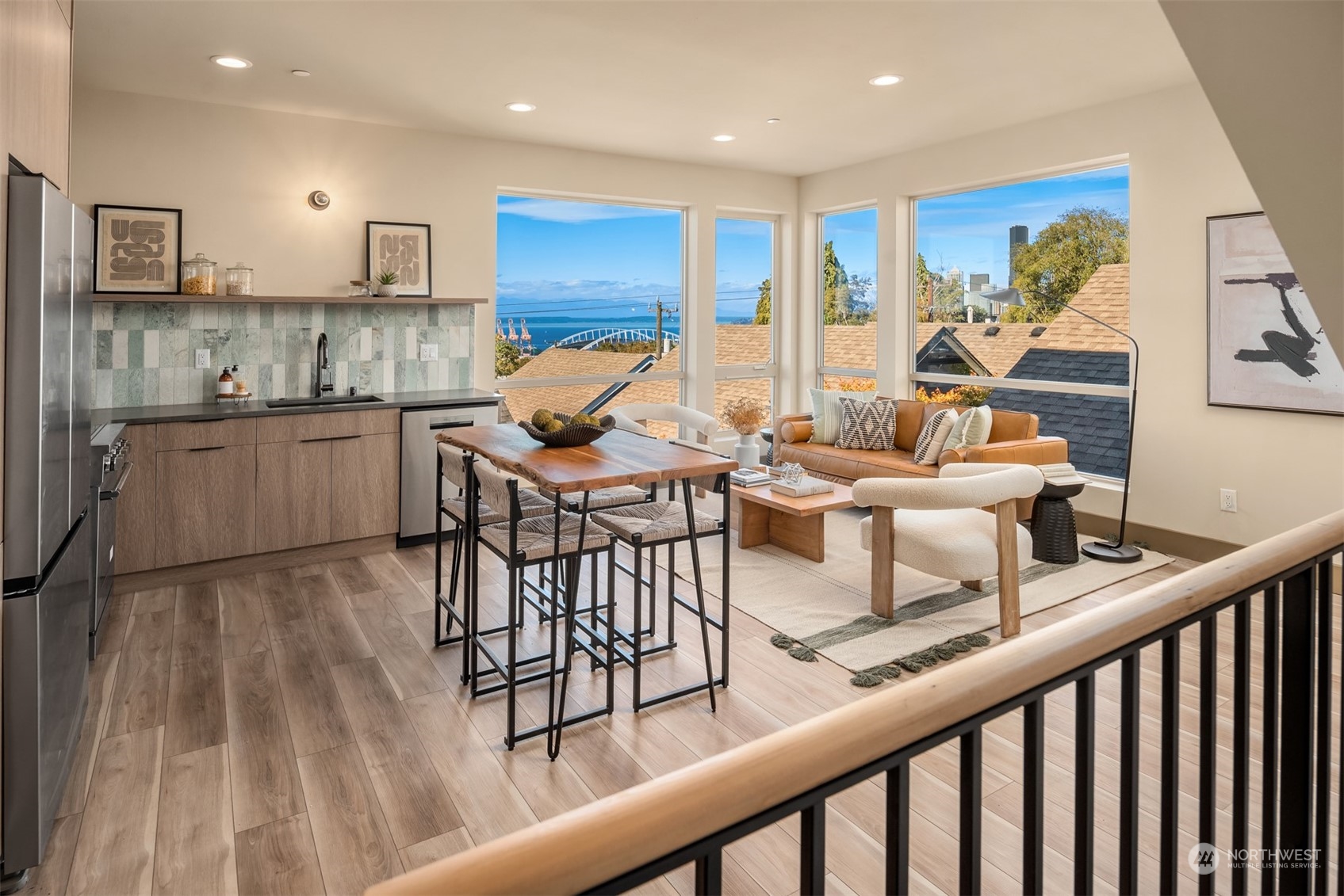 Open-plan kitchen and living area with wide windows overlooking water and a bridge.