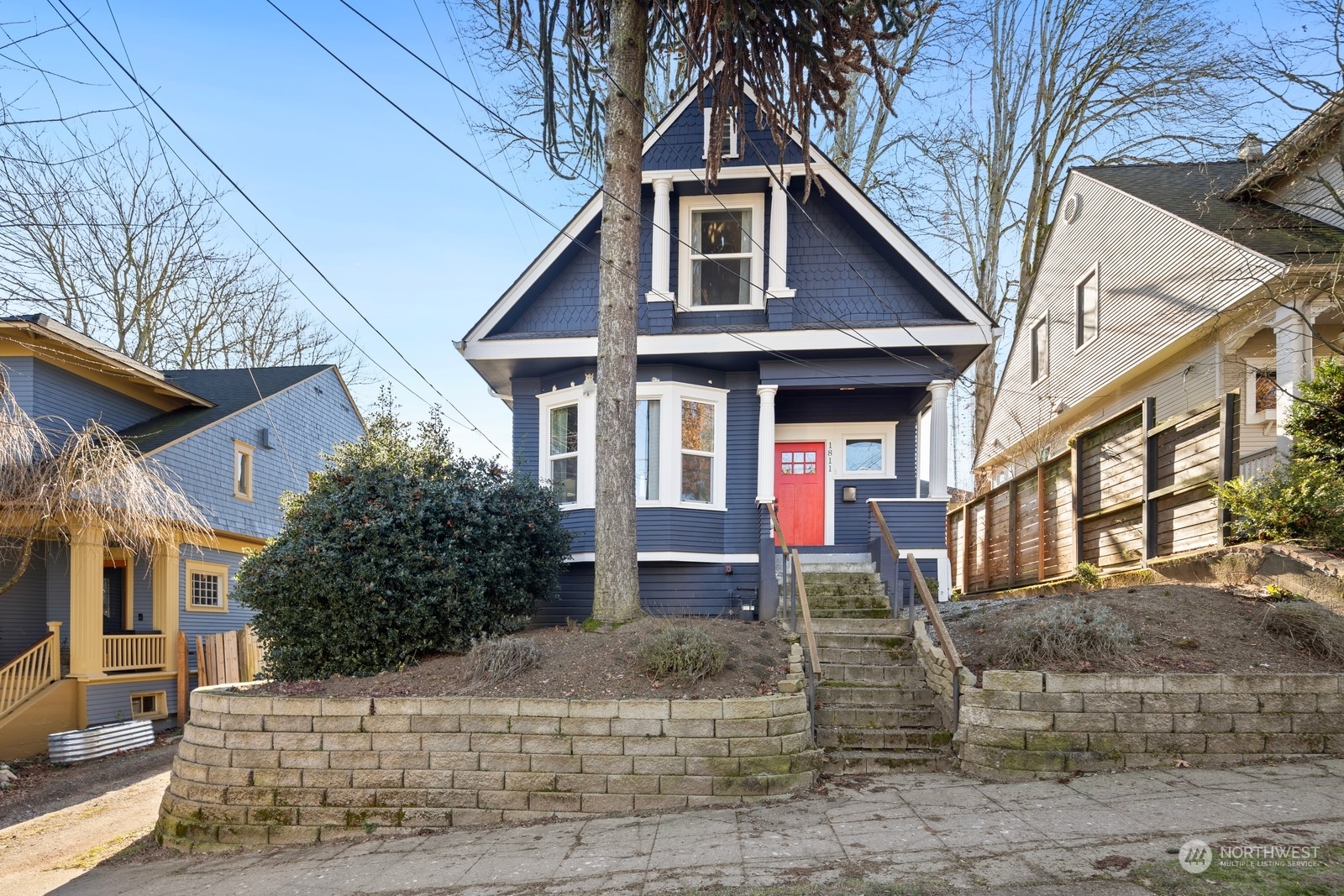 Blue Craftsman-style house with white trim, a red front door, and stone steps.
