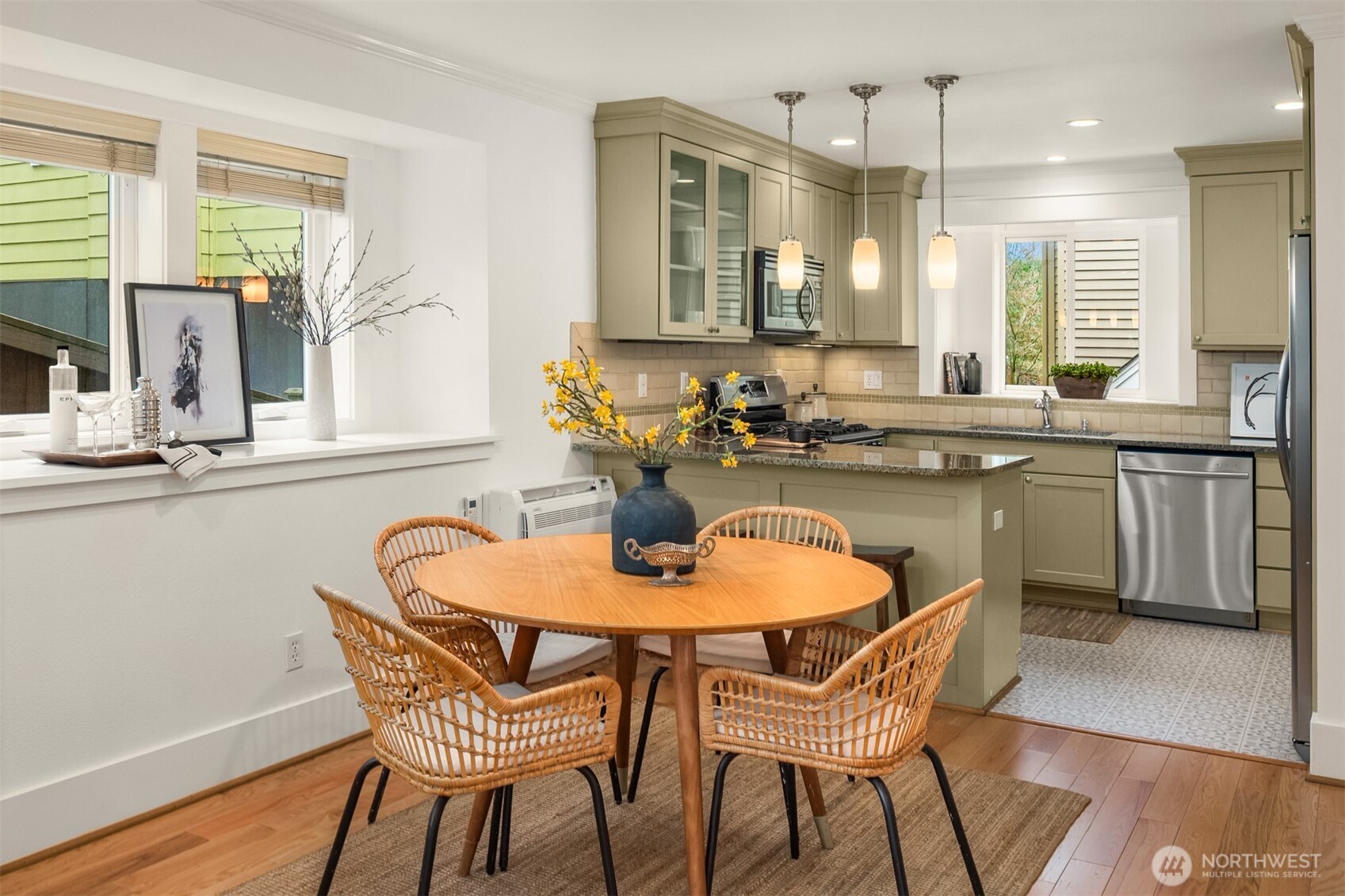 Kitchen and dining area with olive-green cabinets, a peninsula, and a round table surrounded by woven chairs.