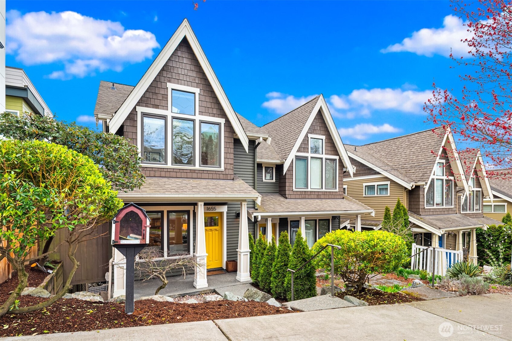 Seattle home with steep front gables, dark shingle siding, and a bright yellow front door.