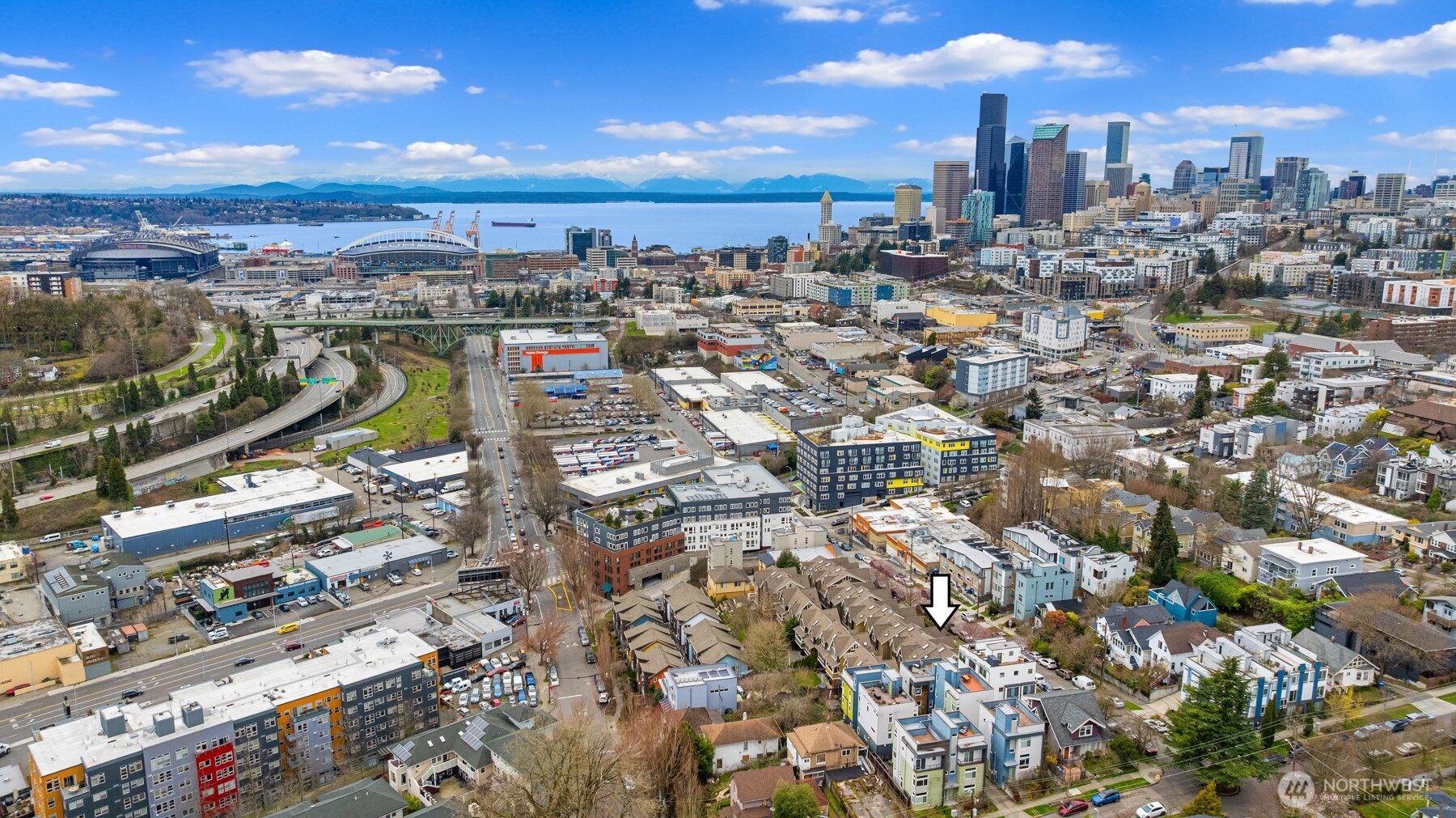 Aerial view of the neighborhood and Seattle skyline, with an arrow marking the property.