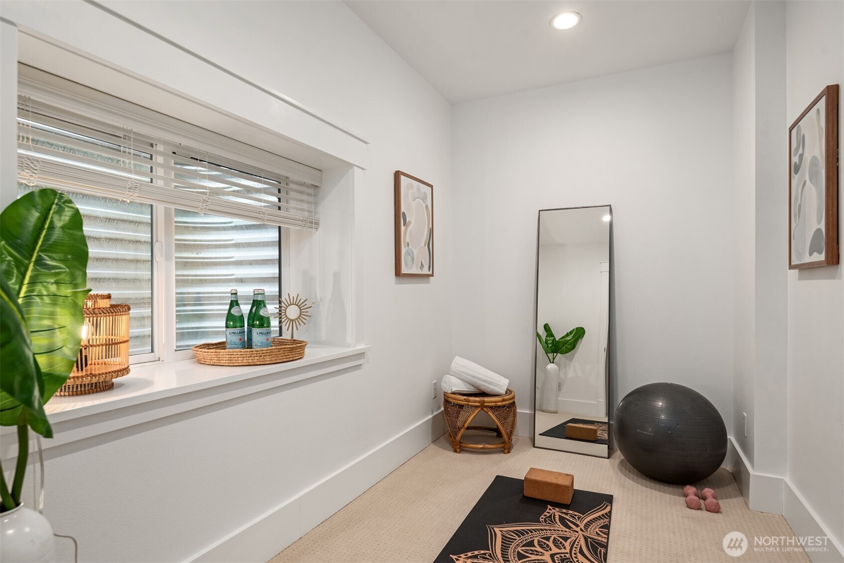 Staged exercise room with a full-length mirror, yoga mat, exercise ball, and large window.