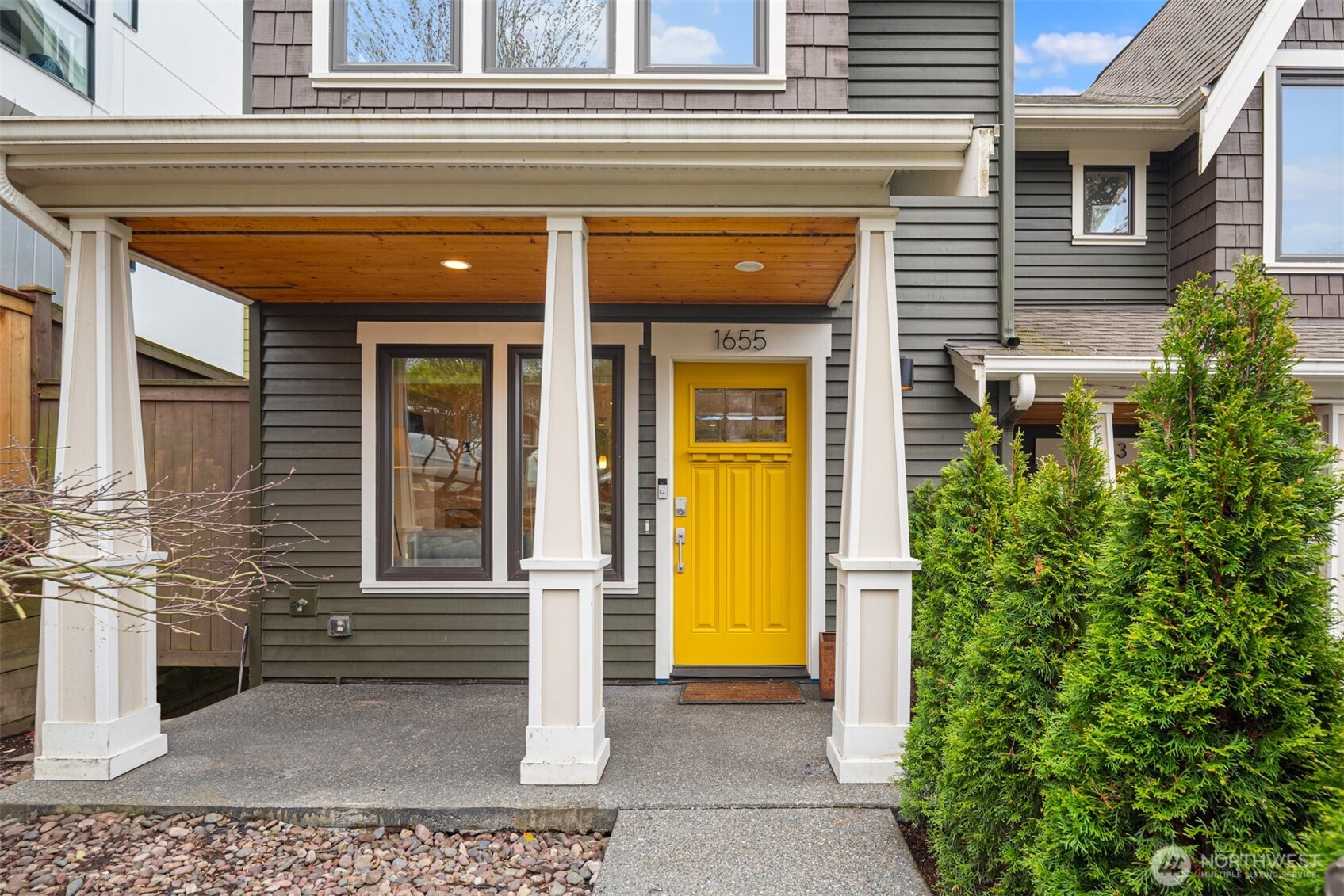 Gray-sided home with a covered porch and bright yellow front door.