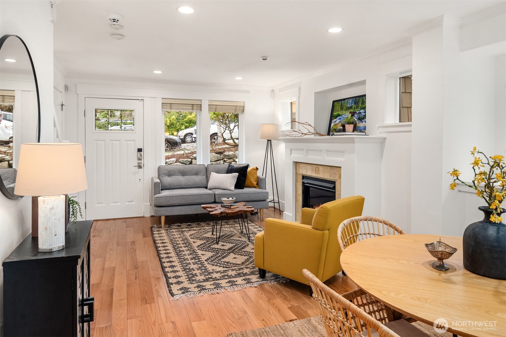 Living room with a white fireplace, gray sofa, mustard armchair, and adjoining round dining table.