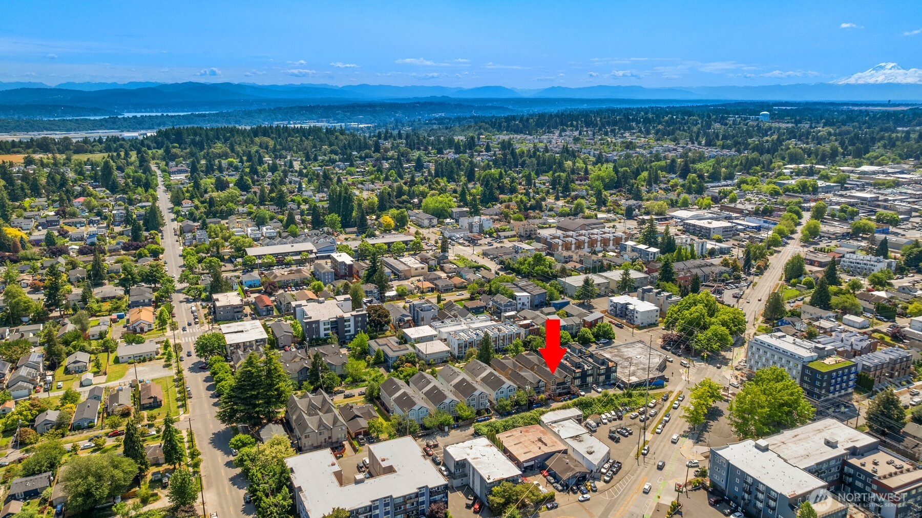 Aerial view of the neighborhood, with a red arrow marking the property and mountains on the horizon.
