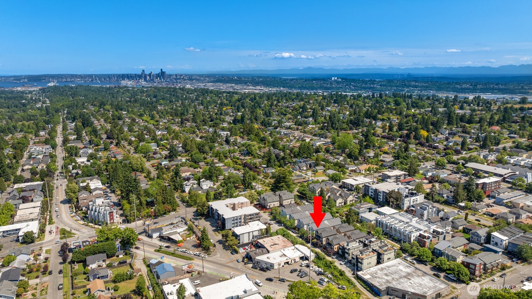 Aerial view of the property marked by a red arrow, with downtown Seattle and water in the distance.