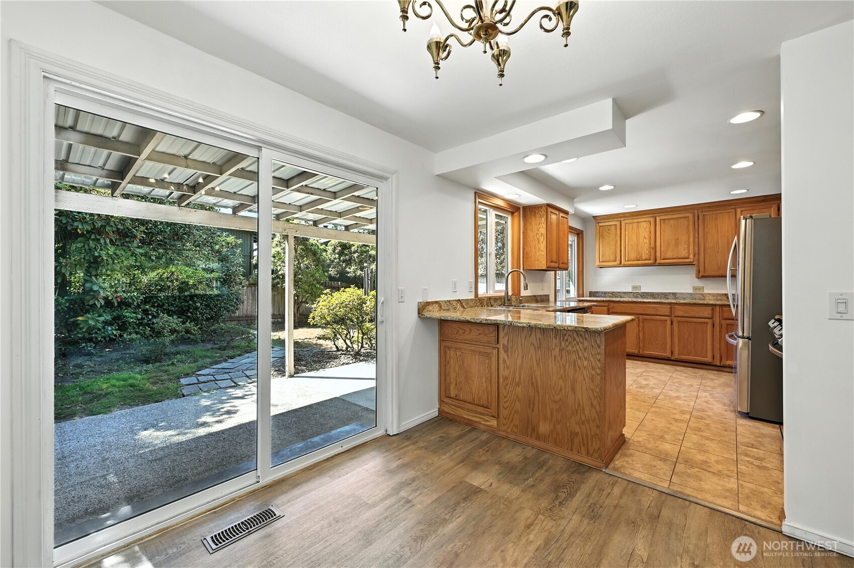 Kitchen with wood cabinets and granite breakfast bar, opening through sliding doors to a covered patio.