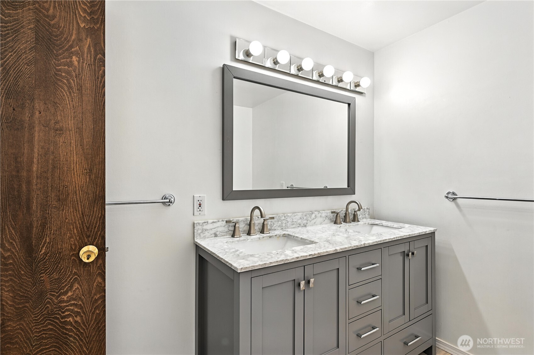 Bathroom double vanity with a marble countertop, dark gray cabinets, and a large framed mirror.