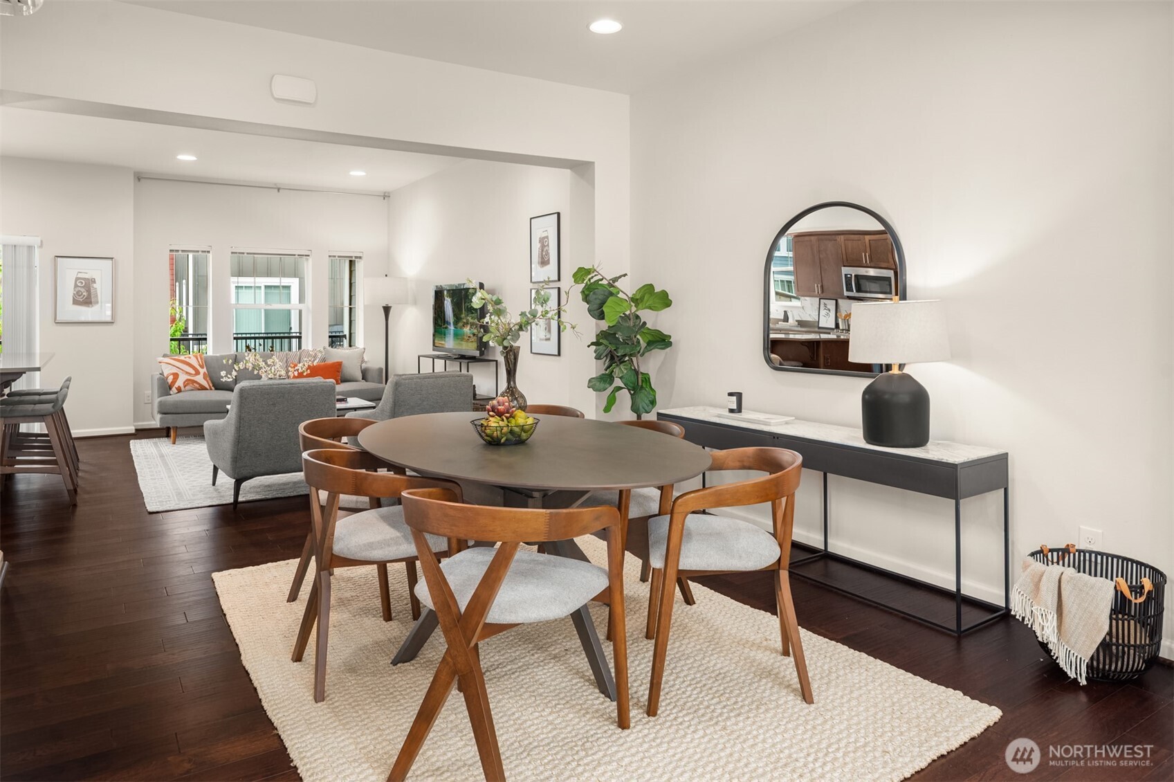 Dining area with an oval table and wood chairs, opening onto a furnished living room.