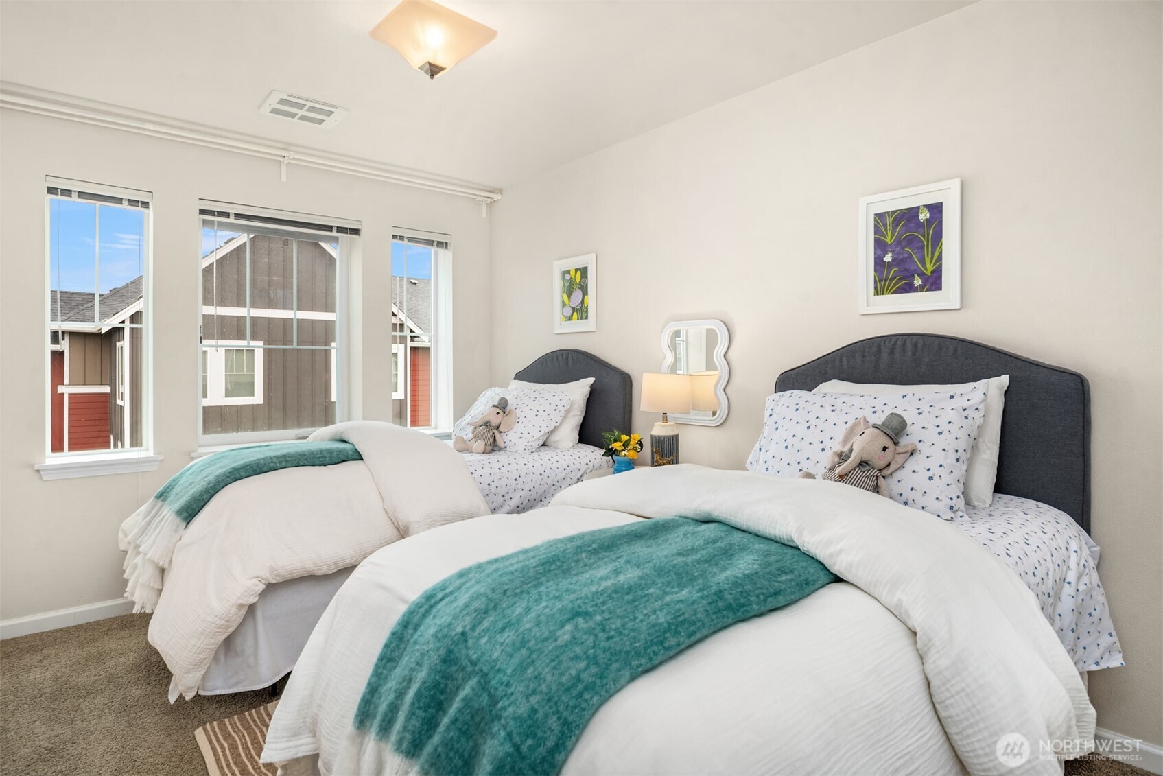 Bedroom with a large bed and twin bed, white bedding, teal throws, and three windows.