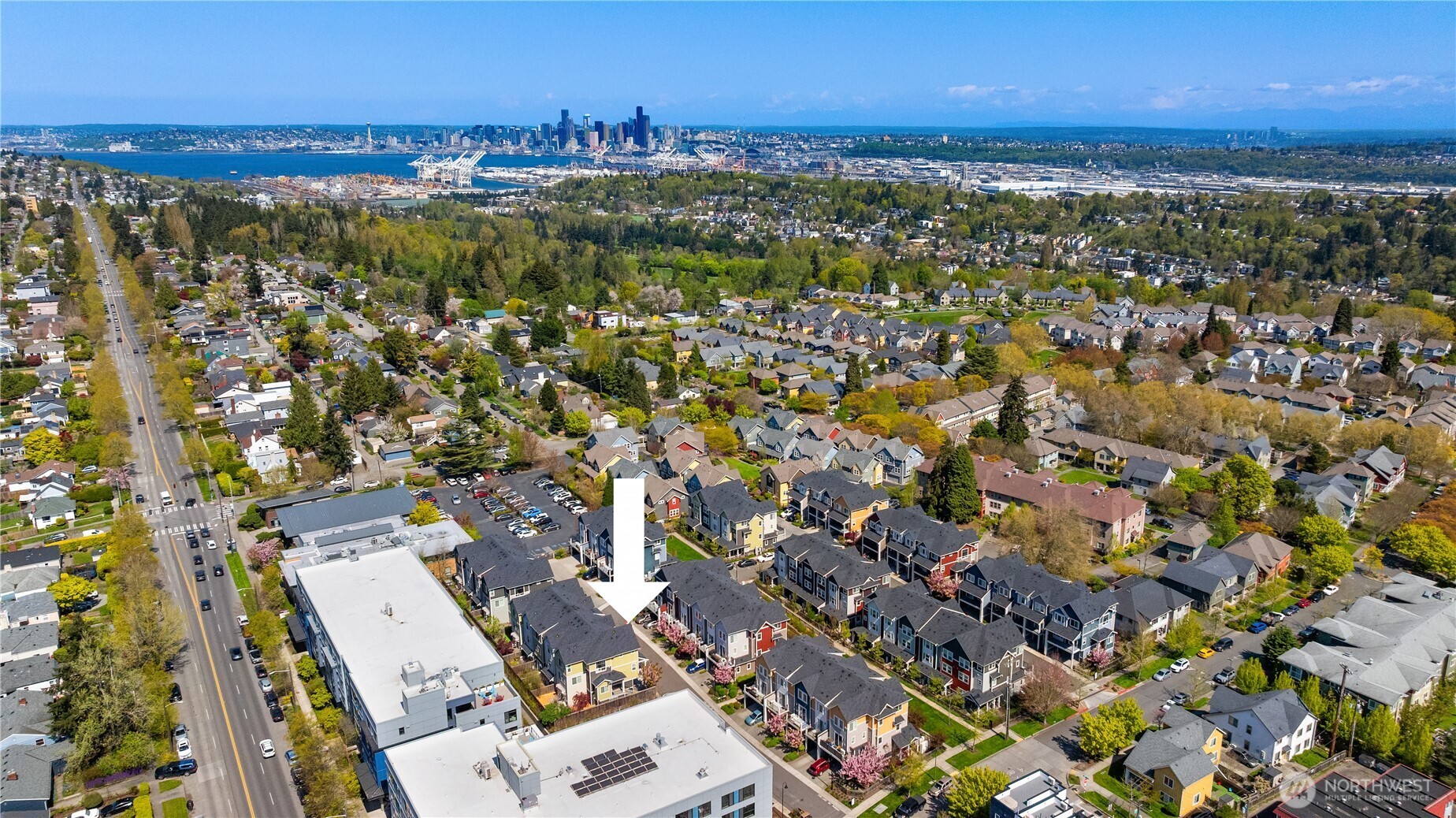 Aerial view of Seattle homes, with an arrow marking one home and downtown skyline in the distance.
