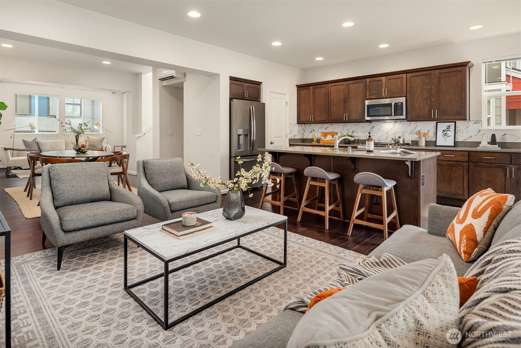 Open-plan living room and kitchen with dark wood cabinets, a large island, and gray seating.