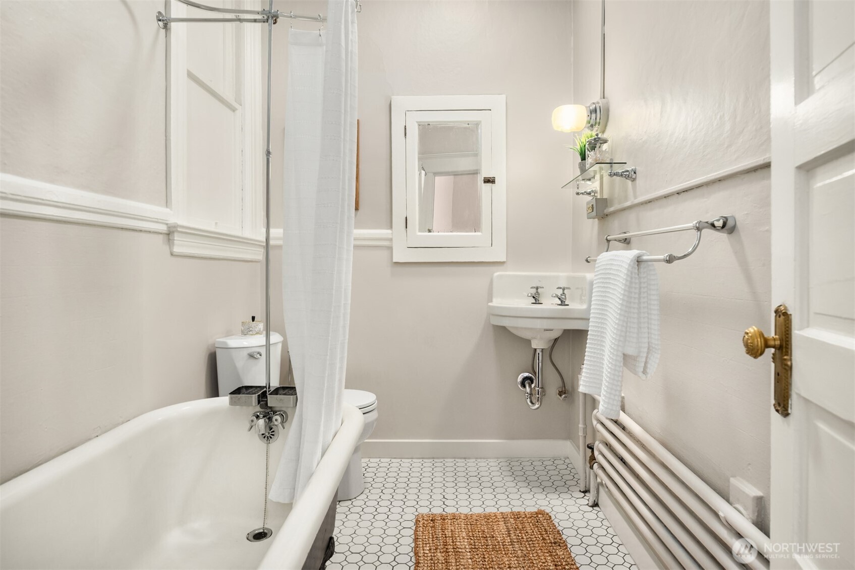 Bathroom with a white bathtub, pedestal sink, and hexagonal tile floor.