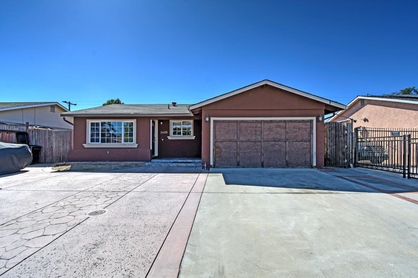 Single-story brown stucco home with a two-car garage and wide concrete driveway.