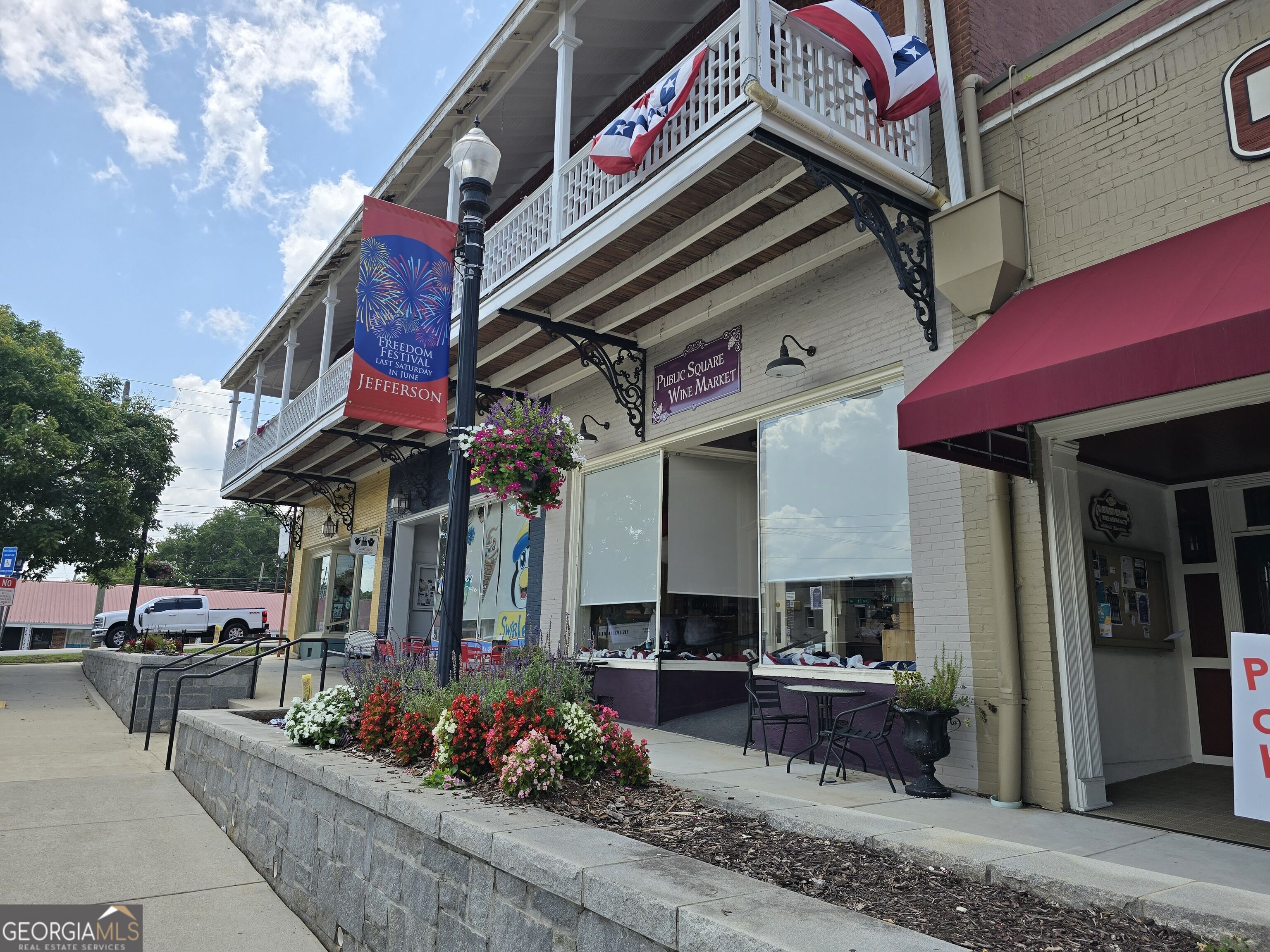 Downtown Jefferson storefronts with balconies, flower planters, and a Public Square Wine Market sign.