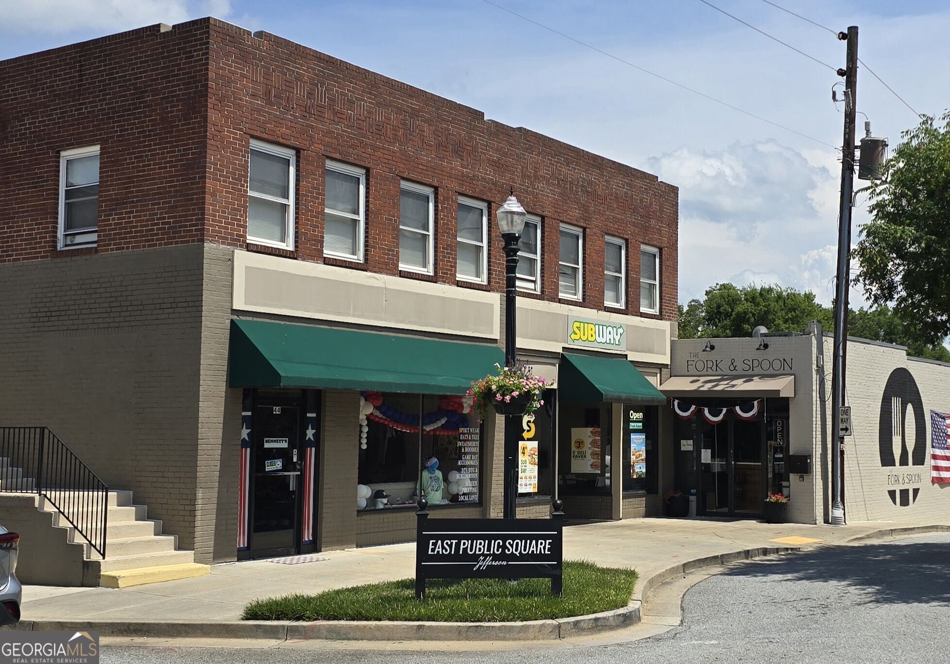 Two-story brick storefronts with green awnings and an East Public Square sign in Jefferson.