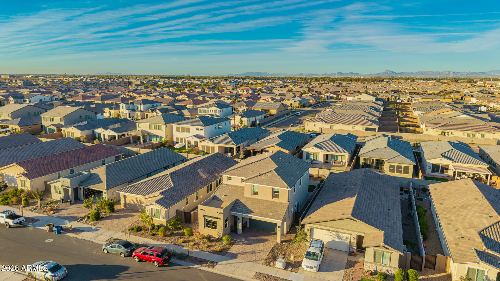 Aerial view of a dense suburban neighborhood with rows of homes and distant mountains.
