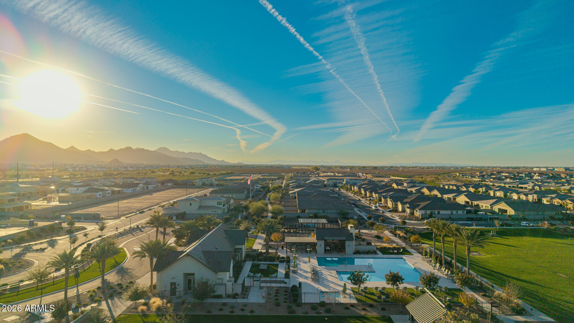 Aerial view of homes and a community pool with mountains on the horizon.