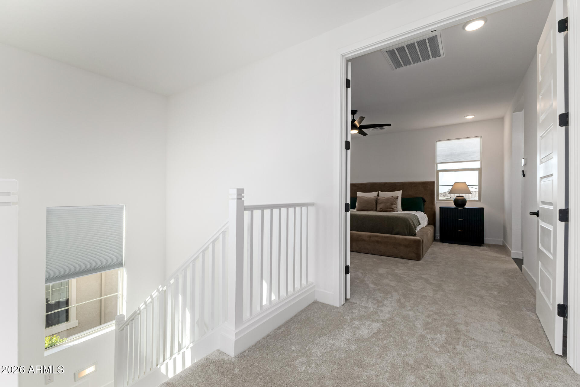 Carpeted upstairs landing opens to a furnished bedroom with a bed and window.