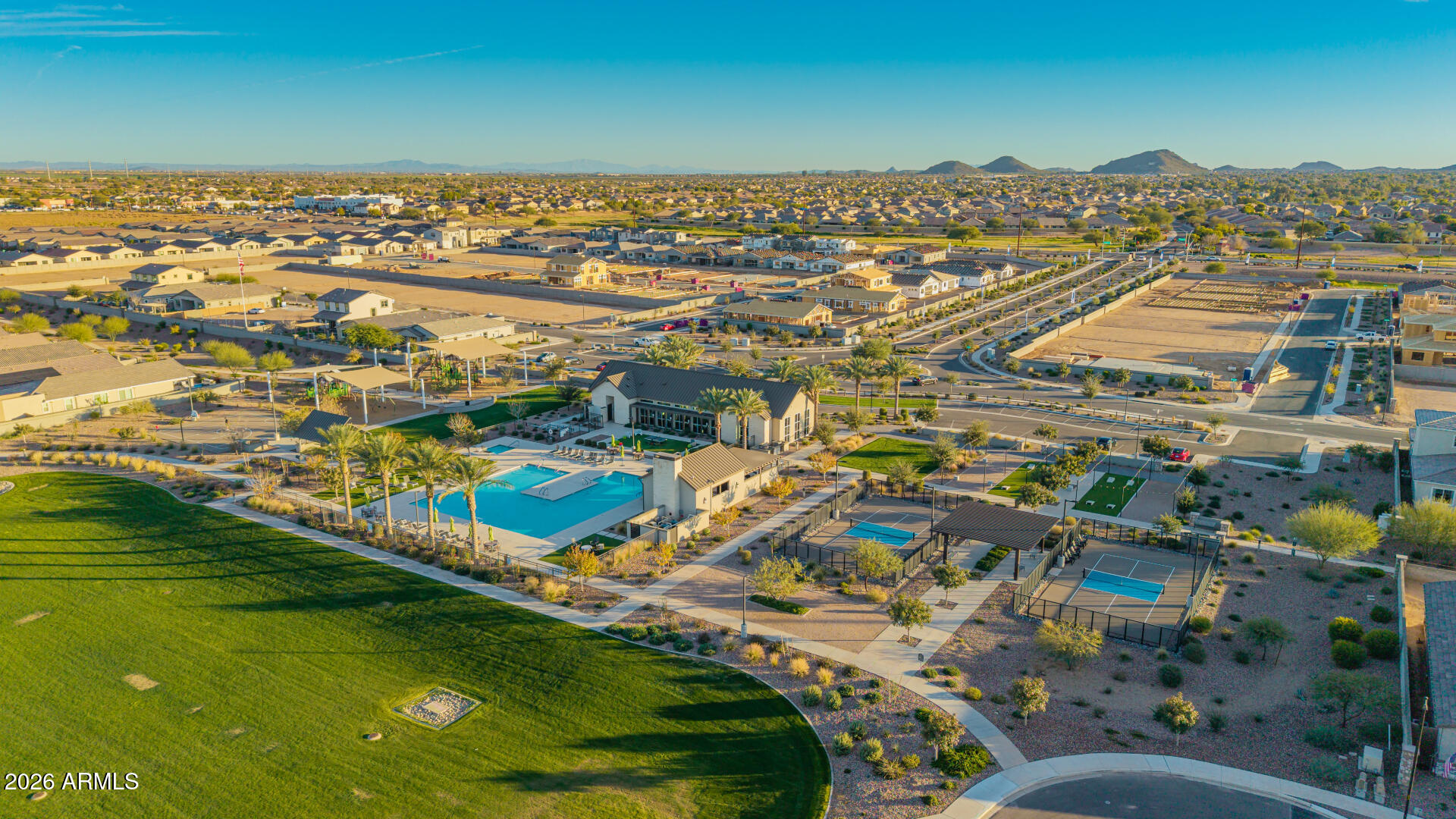 Aerial view of a residential community with a swimming pool, recreation center, courts, and landscaped park.