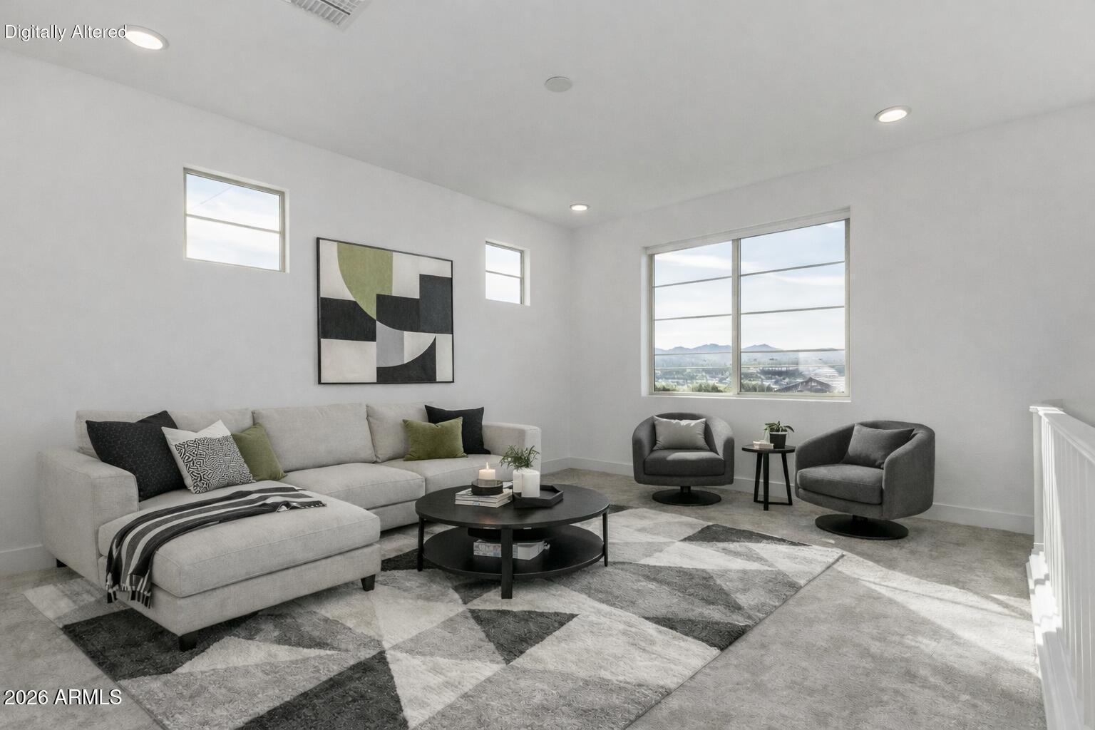 Staged living room with a light sectional, gray swivel chairs, geometric rug, and mountain views through a large window.