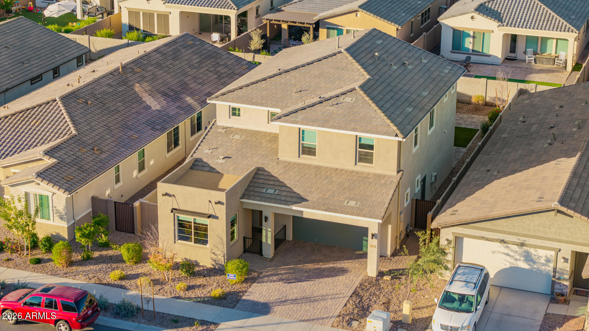Two-story beige stucco home with a tile roof, attached garage, and desert landscaping, viewed from above.
