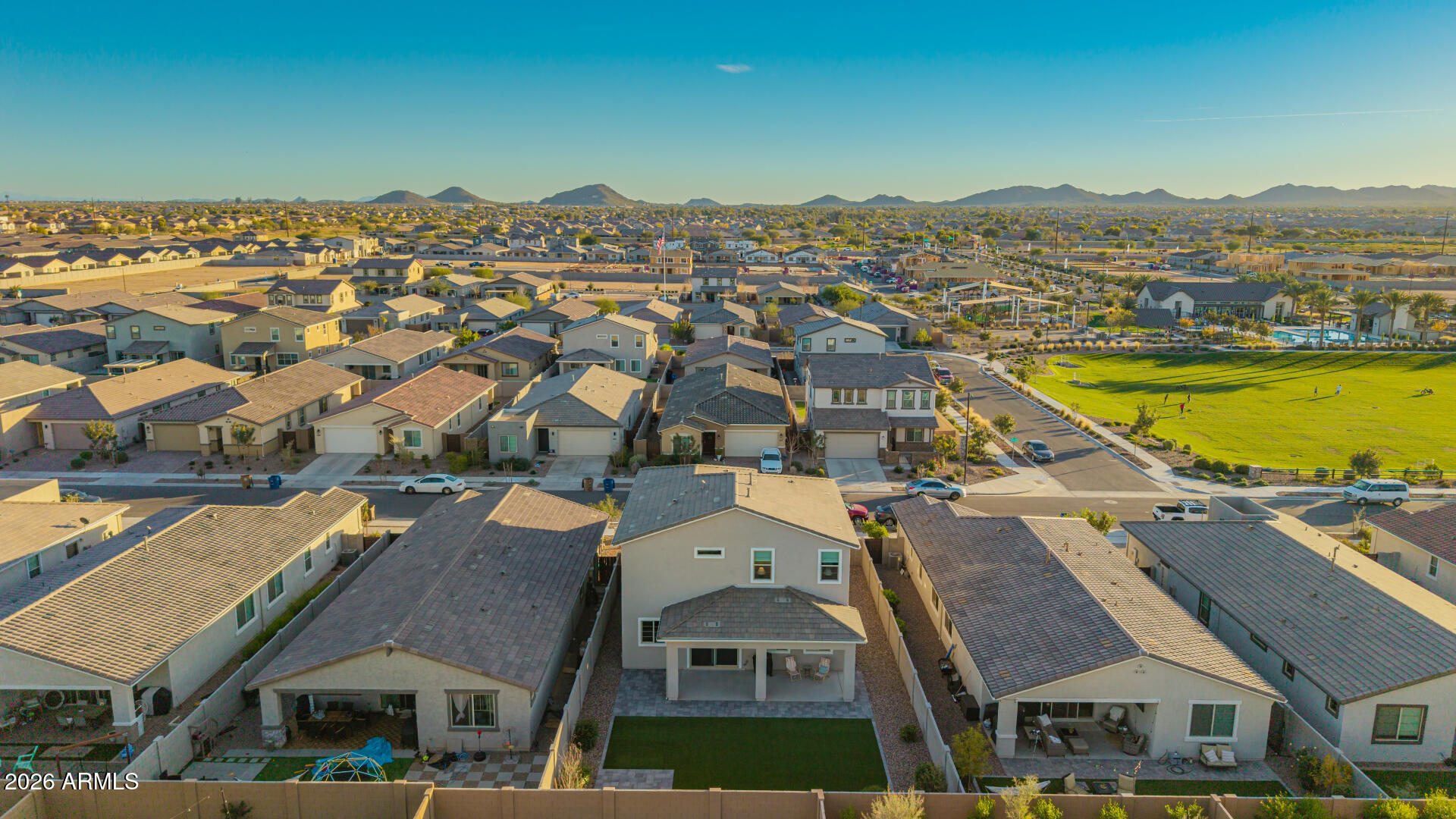 Aerial view of a Queen Creek neighborhood, with the featured home in the foreground and mountains beyond.