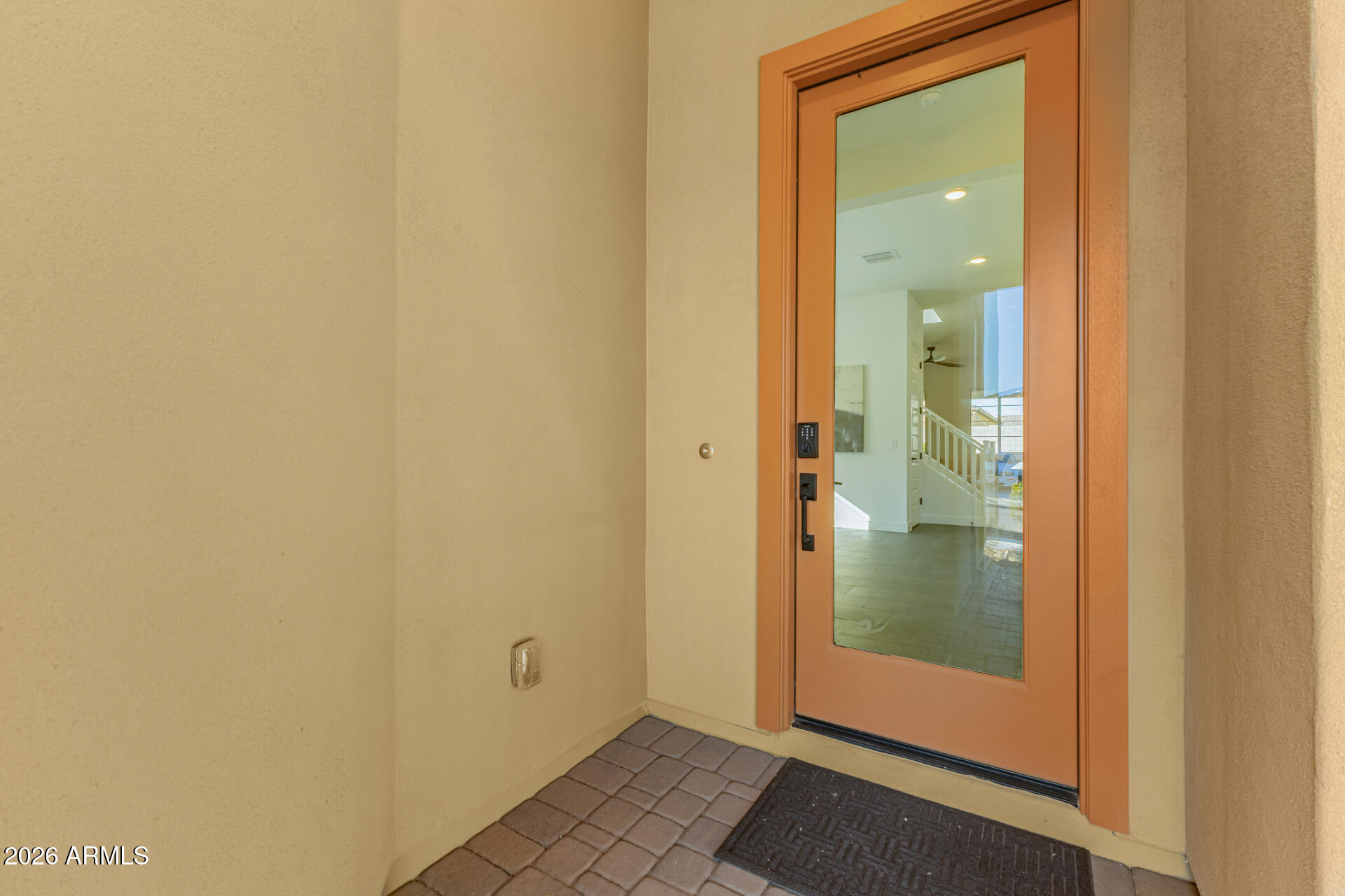 Covered front entry with a terracotta-framed glass door and keypad lock.