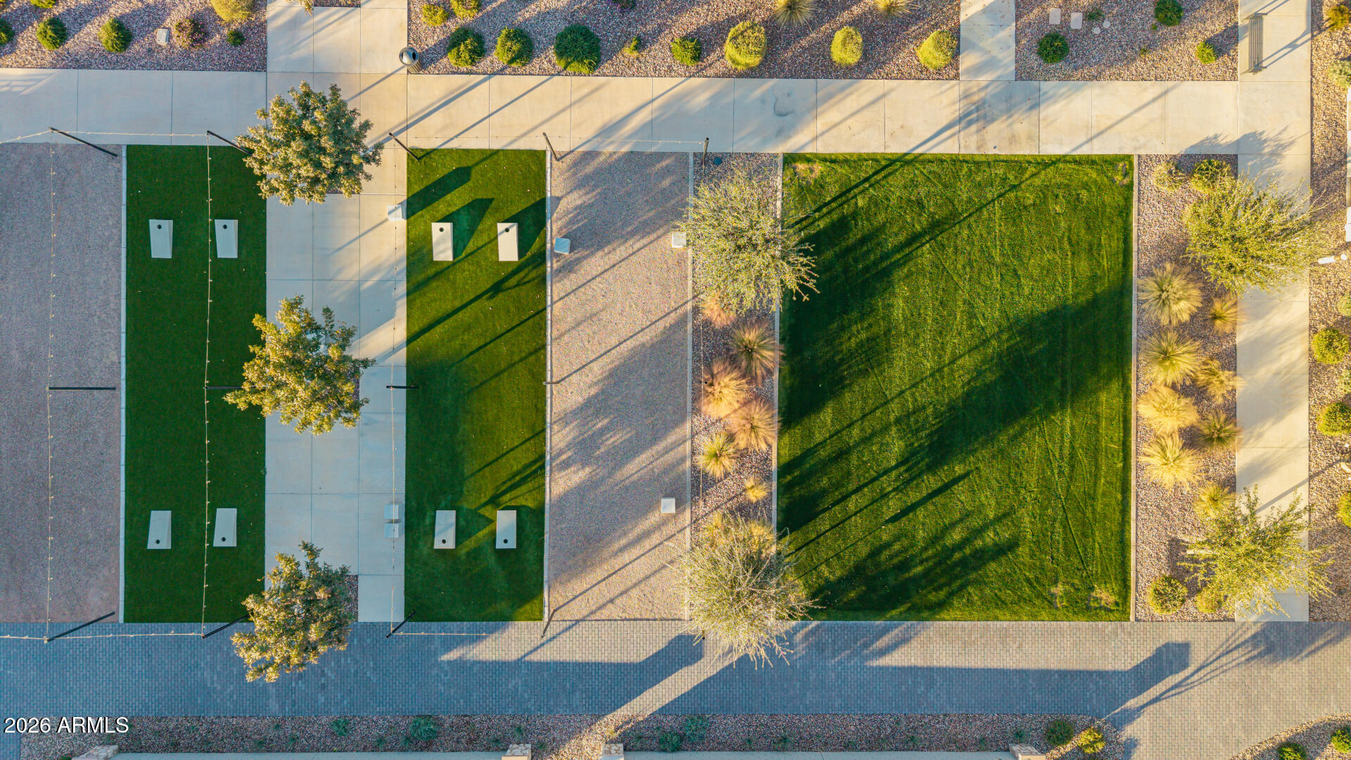 Aerial view of a community lawn and two smaller green courts among desert landscaping.