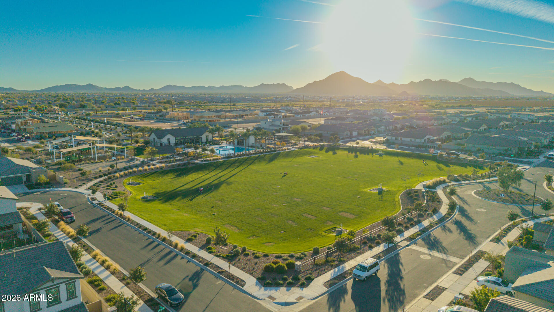 Aerial neighborhood view with a large green park and mountains in the distance.