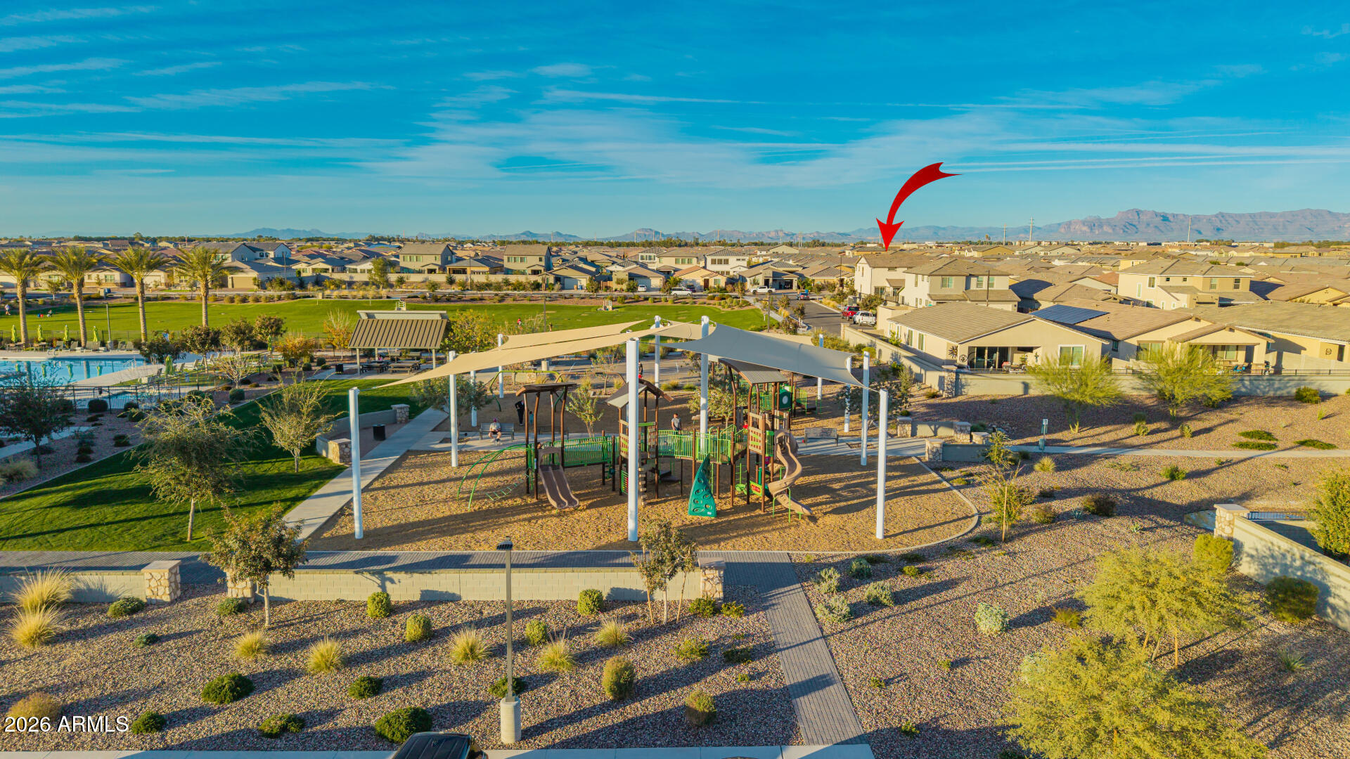 Aerial neighborhood view with the listed home marked by a red arrow beyond a park and pool.