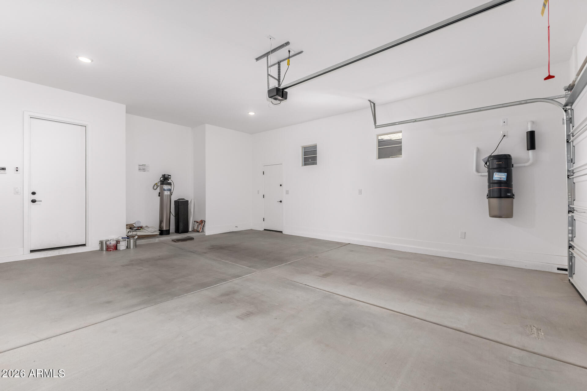 Empty garage with a concrete floor, overhead door, and wall-mounted utility equipment.