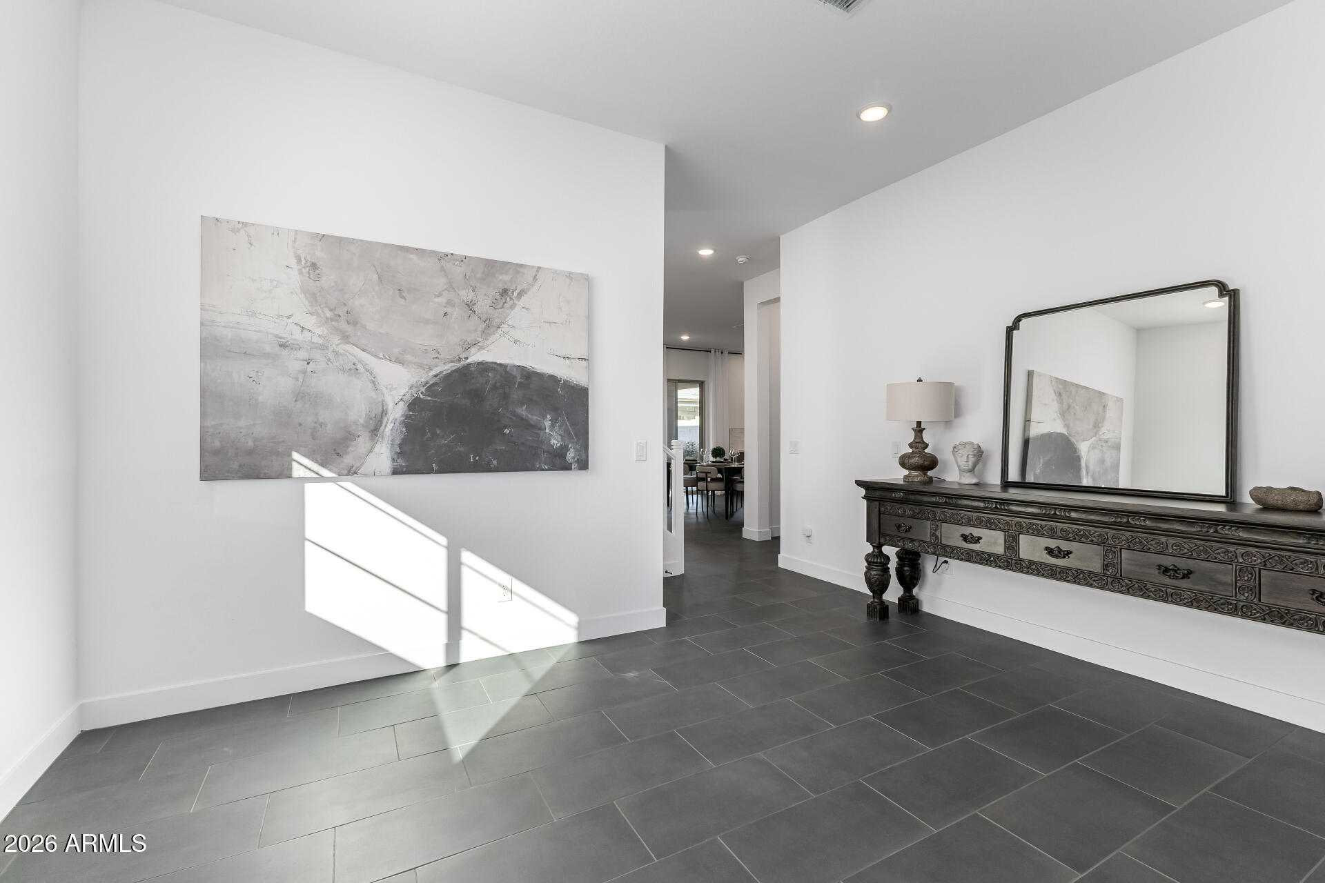 Entry hall with dark tile floors, abstract wall art, and an ornate console beneath a large mirror.