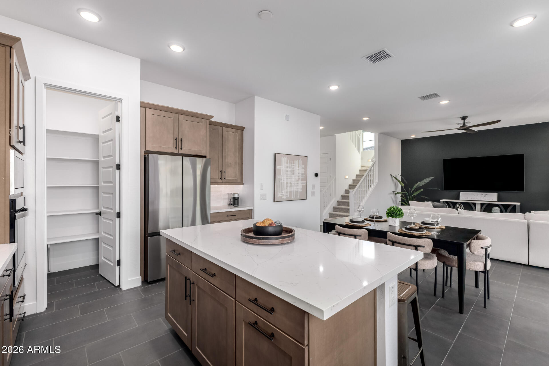 Open-plan kitchen with a large white island, taupe cabinets, and dining and living areas beyond.