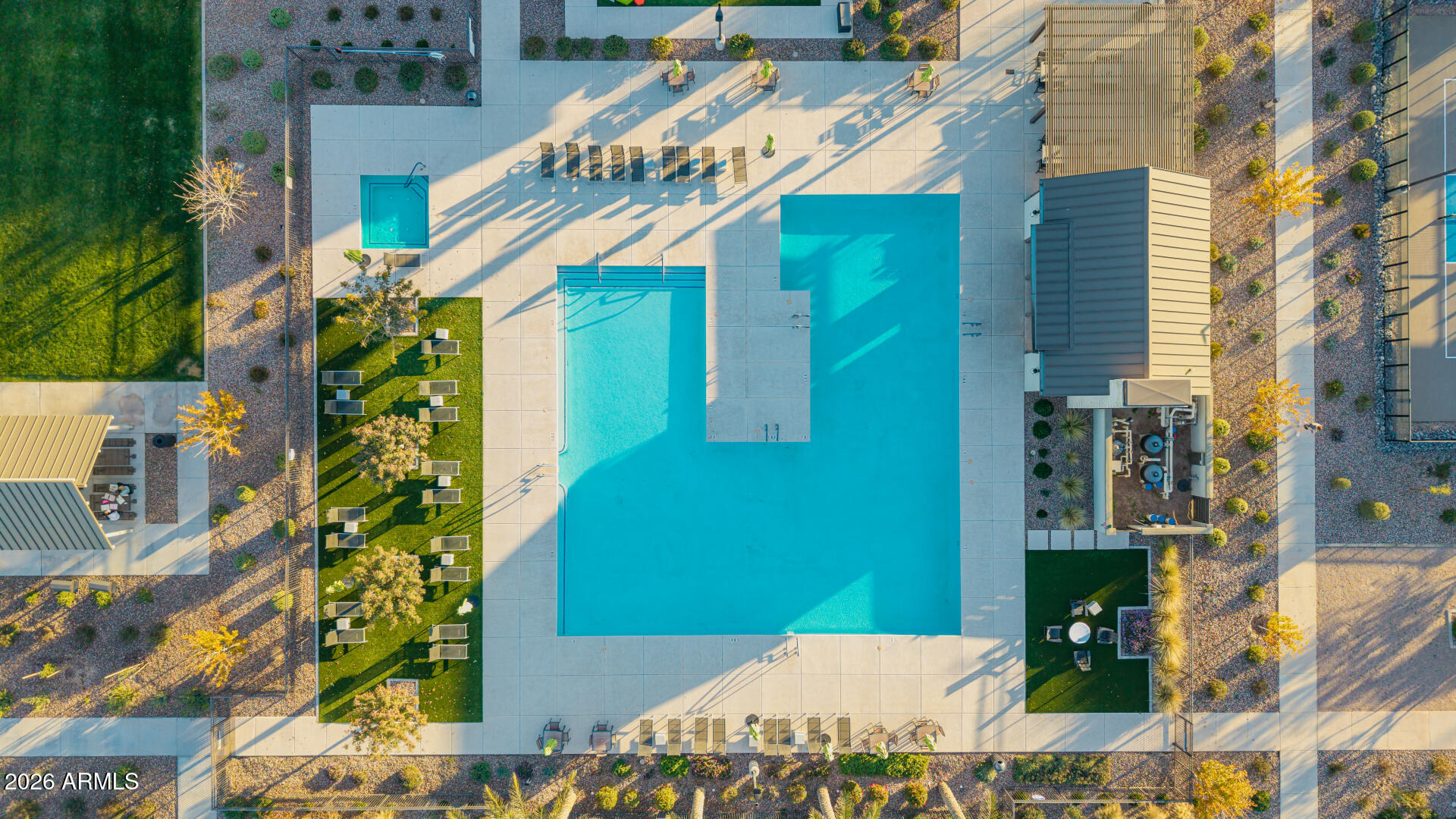 Aerial view of a pool courtyard with a spa, lounge chairs, and pergola.
