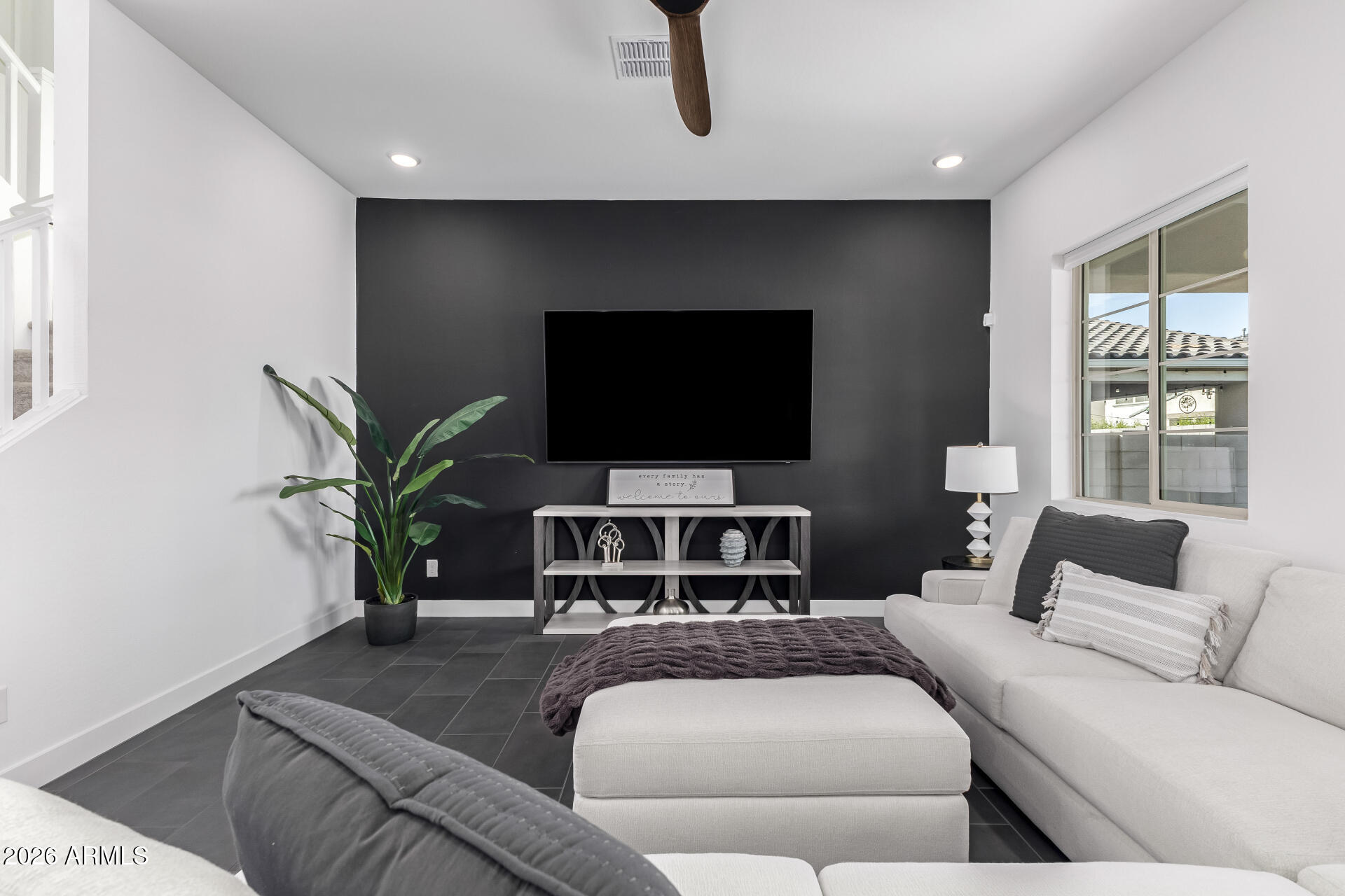 Living room with a charcoal television wall, white sectional, dark tile floor, and potted plant.
