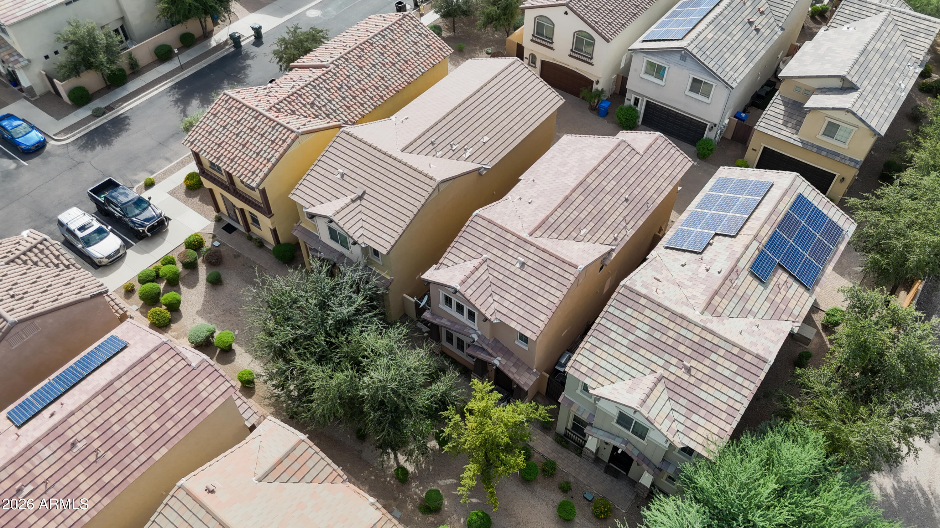 Aerial view of homes with tiled roofs, desert landscaping, and solar panels.
