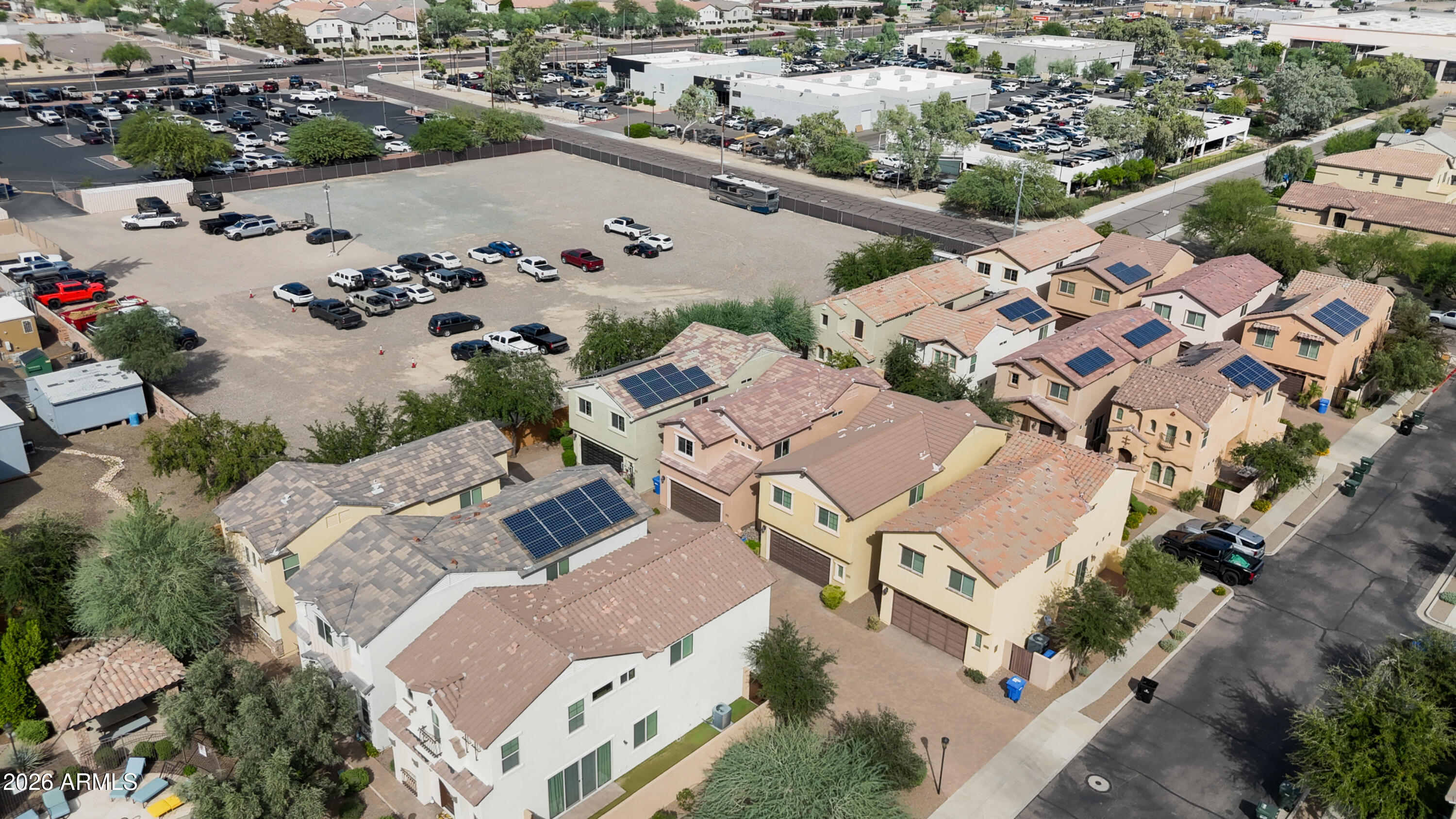 Aerial view of homes with rooftop solar panels beside a large open lot.