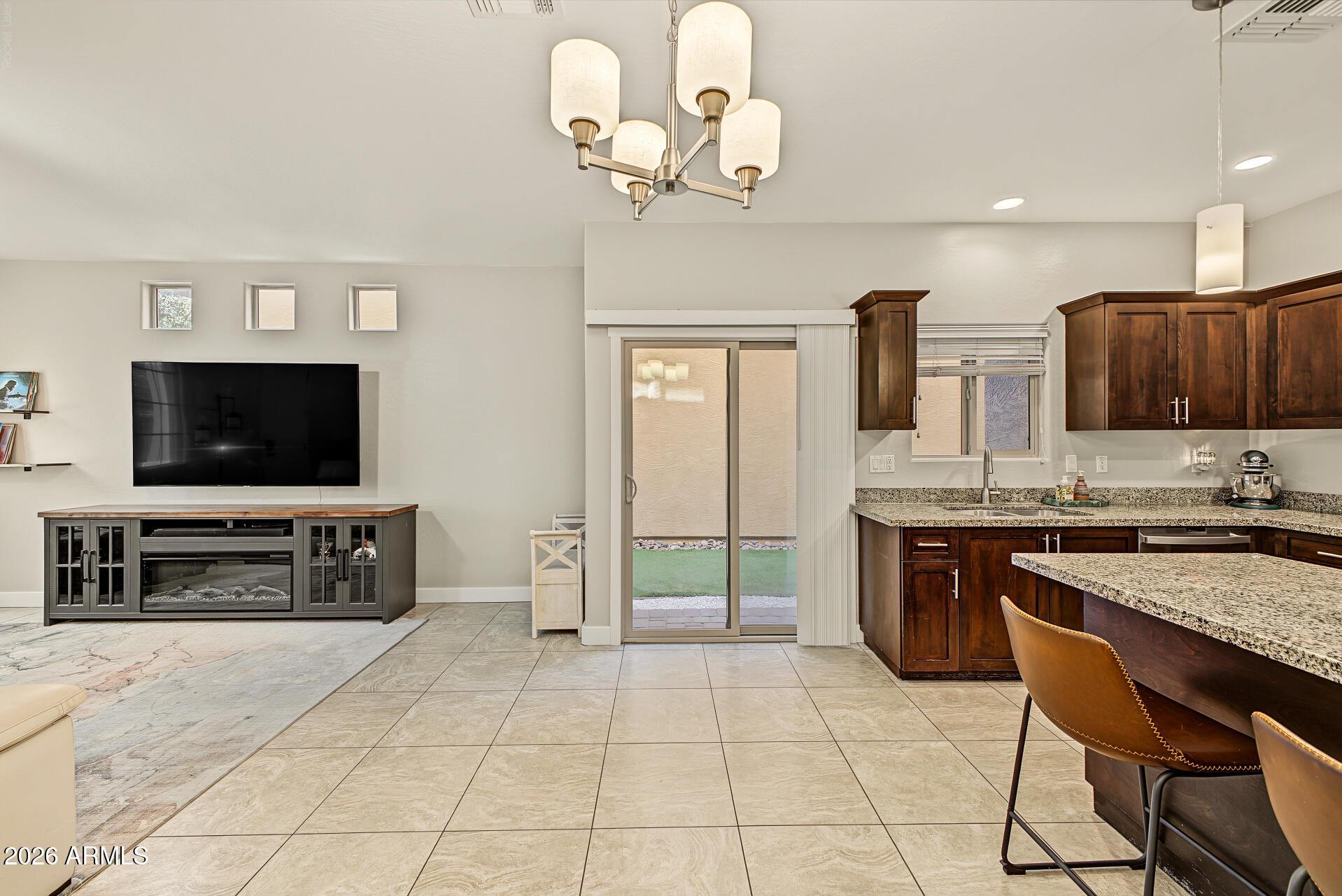 Open-plan living room and kitchen with dark wood cabinets, granite island, and sliding glass doors.